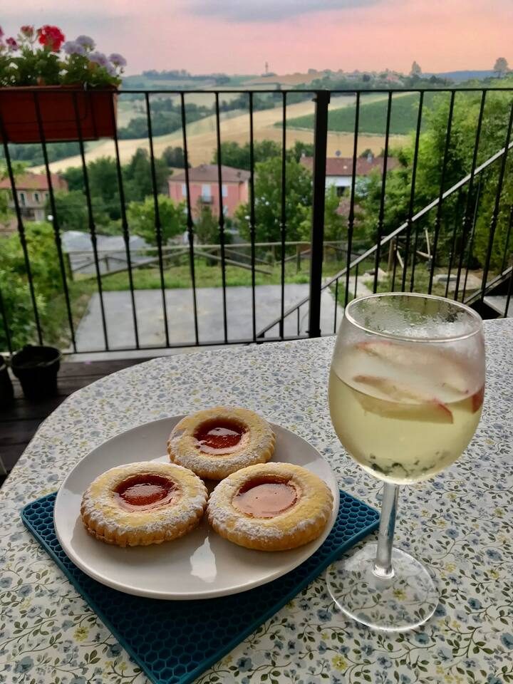 A glass of white wine and jam tarts on the terrace as the sun sets over the hills